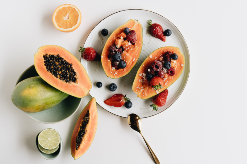 Papaya cut open on a plate with other fruits