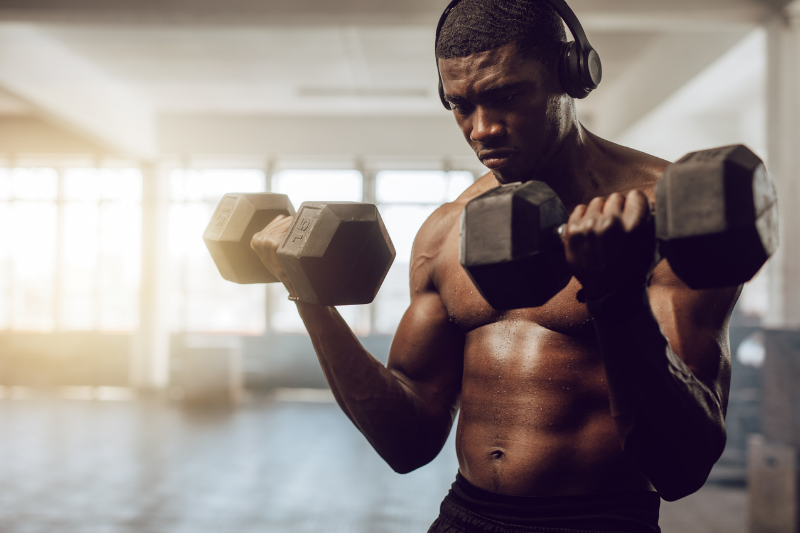 Male with headphones lifting weights