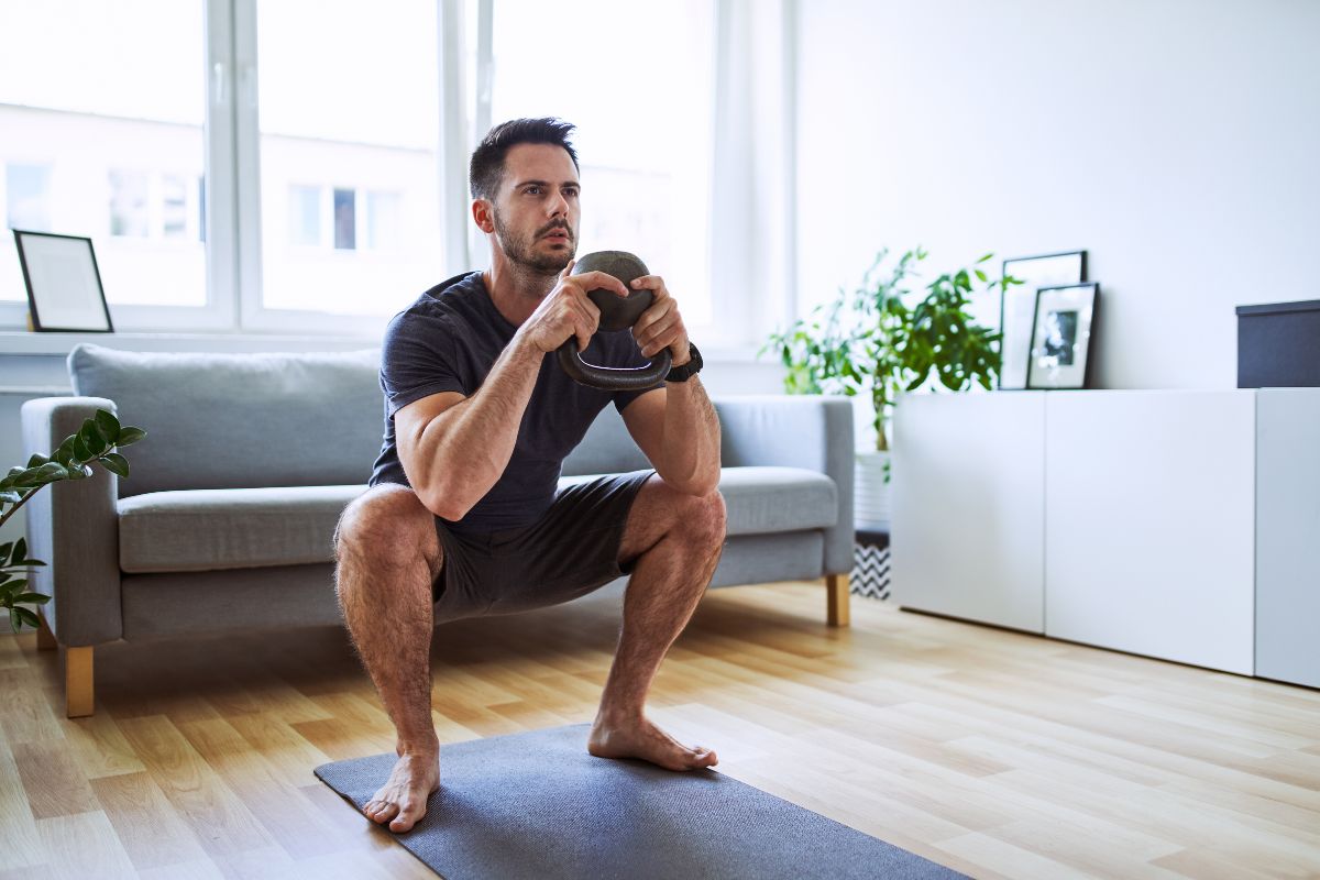 Man doing a squat at home holding a kettlebell