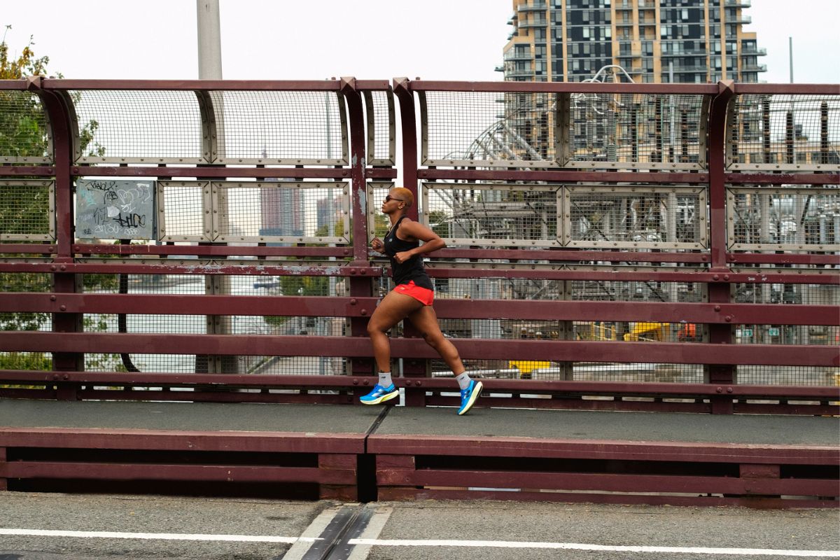 Man running over bridge wearing New Balance FuelCell Rebel v4 