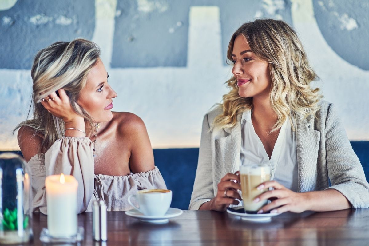 Two women chatting at a cafe with coffee