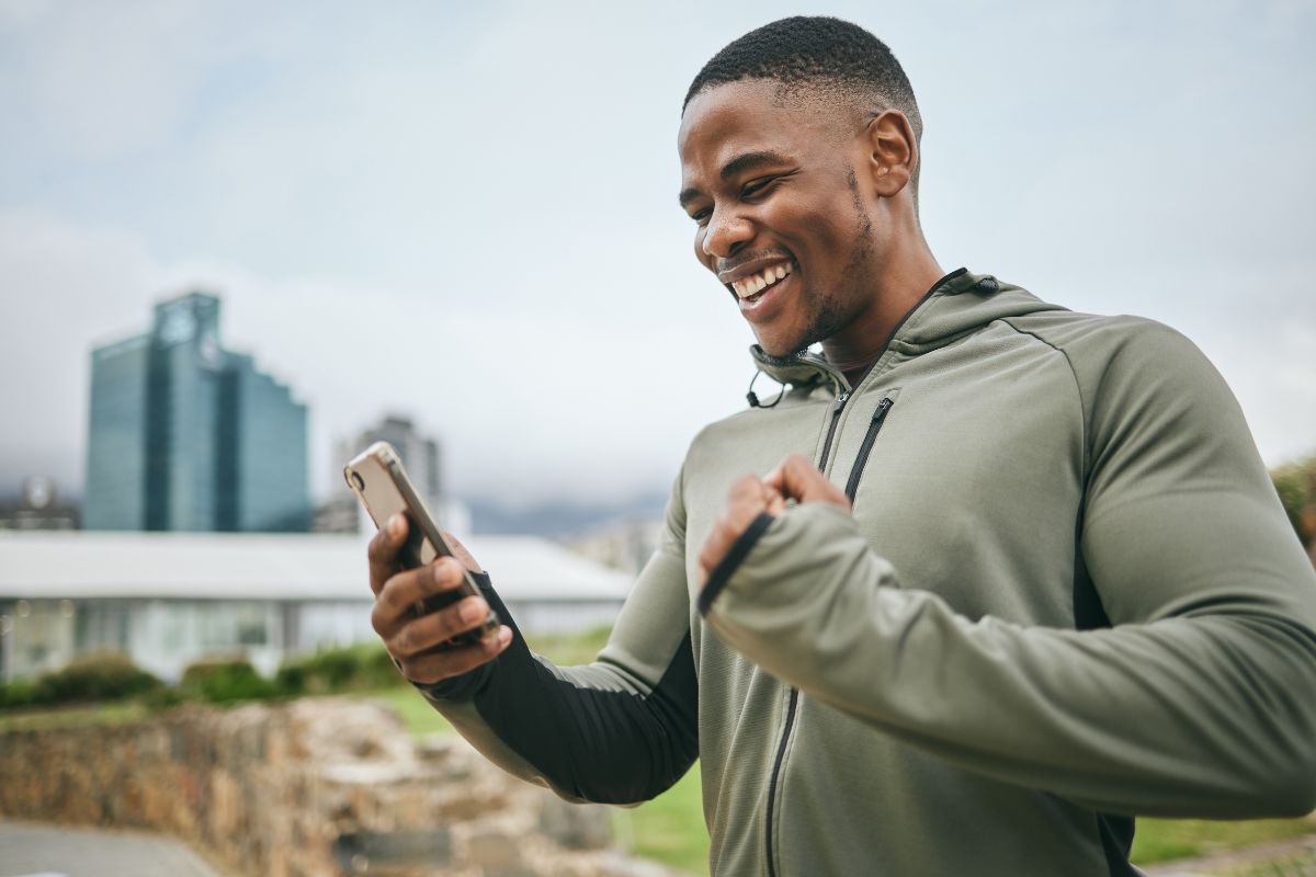 Man excited looking at phone while on a run