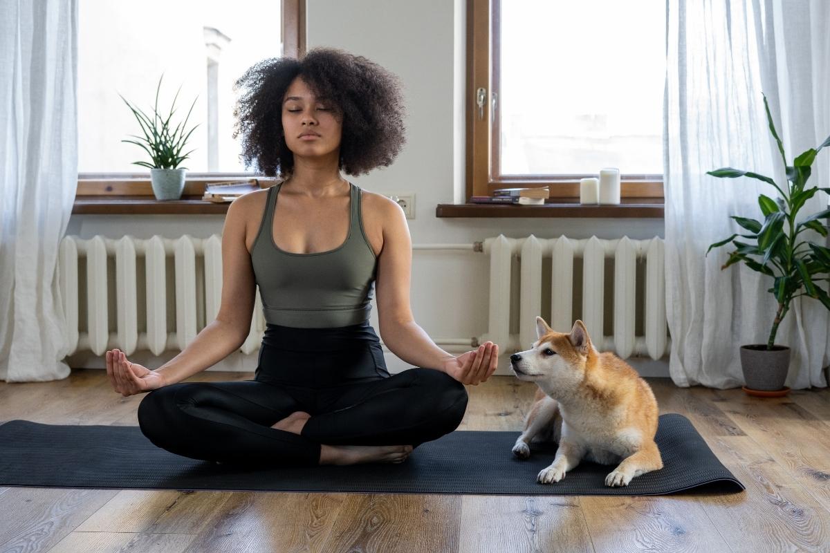 woman meditating with dog beside her